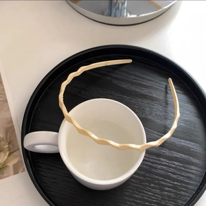 Close-up of a cream wavy thin headband on a wooden tray for a sweet Korean style look