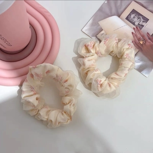 Détail de deux chouchous en tulle crème avec des motifs de fleurs roses
