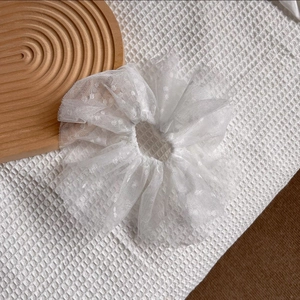 Détail du chouchou en dentelle blanche élégante avec des broderies délicates de pois