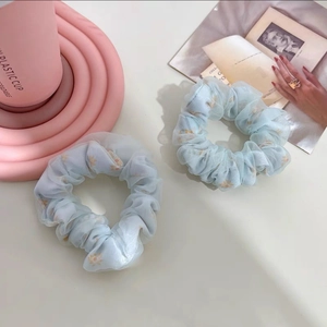 Détail de deux chouchous en organza bleu clair avec des motifs floraux de marguerites