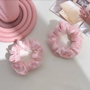 Détails de deux chouchous en organza rose avec des motifs de marguerites délicates