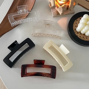 Flat lay of 12.5cm hollow rectangular hair claws in five colors on a wooden tray