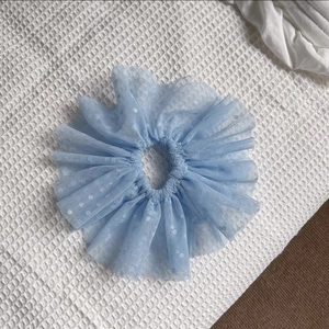 Gros plan sur chouchou en dentelle bleu clair à pois blancs et texture en maille