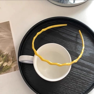 Detail of bright yellow wavy headband placed on a white ceramic mug in a lifestyle setting