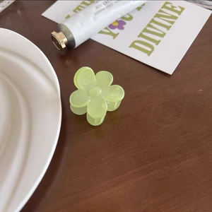 Vue détaillée d'une pince à cheveux en forme de fleur vert clair sur une table