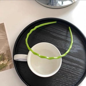 Detailed close-up of a bright green wavy headband on a modern minimalist tabletop