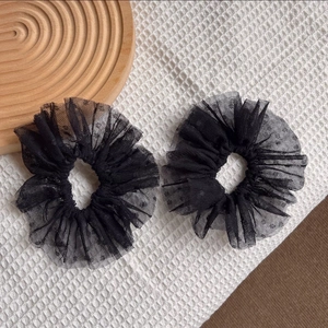 Détail de deux chouchous en dentelle noire avec tulle à pois et bords à volants