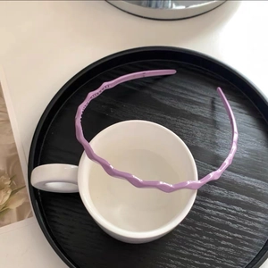 Detailed close-up of a purple wavy headband with non-slip teeth on a white mug