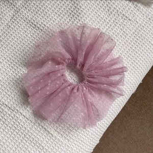 Détail du chouchou en dentelle rose avec texture à pois sur un tissu de fond blanc