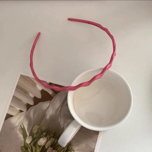 Close-up of pink wavy headband with a glossy finish and minimalist candy style design