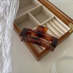 Detailed view of a 12.5cm amber resin hair claw clip resting on a wooden jewelry box