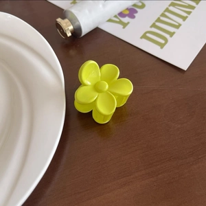 Gros plan d'une pince à cheveux fleur jaune mat sur fond de table en bois rustique