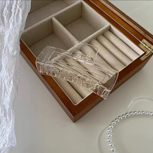Macro shot of large transparent acrylic hair claw clip on luxury wooden jewelry box