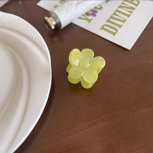Détail d'une pince à cheveux fleur jaune clair sur une table en bois décorée avec soin