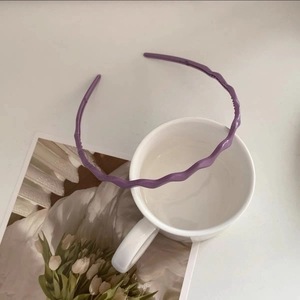 Detail view of purple wavy resin headband with non-slip teeth on a white mug backdrop