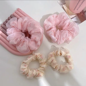Gros plan de chouchous en organza fleuri avec motifs marguerites roses et texture maille