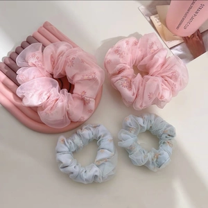 Détail de quatre chouchous en tulle à motif marguerites en rose et bleu clair