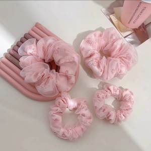 Détail de quatre chouchous en organza rose avec imprimés marguerites en lot