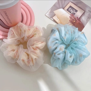 Détails de grands chouchous en organza à fleurs superposés dans des tons pastels