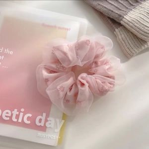 Détail d'un chouchou géant en résille rose avec des motifs floraux de marguerites douces