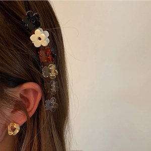 Close-up of mini flower hair claws and gold geometric stud earrings on a model