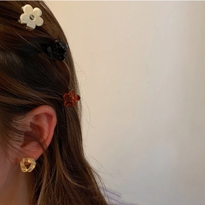 Side view of a woman wearing mini floral hair claws and a golden twist earring accessory