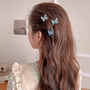 Mini butterfly hair clips with iridescent blue and purple gradient on wavy hair