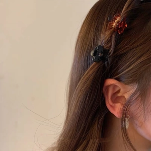 Close-up of mini flower hair claws in amber and black colors worn on model hair