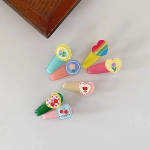 Flat lay of colorful children's hair clips featuring rainbow heart and cherry patterns