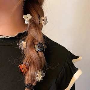 Close-up of mini flower hair claws in cream and amber styling a side braid hairstyle