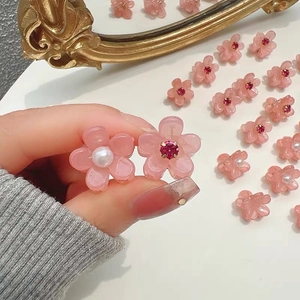 Dettaglio di mini mollette per capelli a fiore rosa con perle e strass in mano