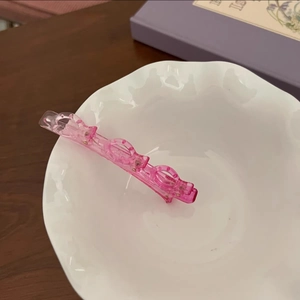 Vue détaillée d'une pince à cheveux rose translucide dégradée dans un bol en céramique