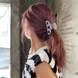 Détail d'une grande pince à cheveux en acétate avec motifs de cœurs creux verts sur violet