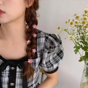 Dettaglio delle mini mollette per capelli a fiori rosa con perle su acconciatura a treccia