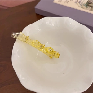 Gros plan d'une pince à cheveux jaune translucide en acrylique sur un bol en céramique