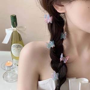 Close-up of mini butterfly hair clips with pink and blue gradient in a braided hairstyle
