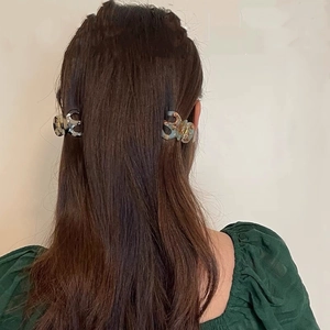 Detail of elegant small hair claw clips in marble pattern on high ponytail hair
