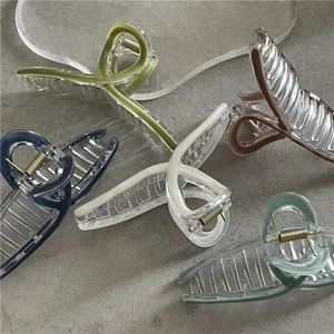 Five colorful acrylic hair claws for summer styling on a minimal grey surface