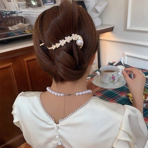 Elegante gouden haarstok met parels gedragen in een verfijnde knot haarstijl