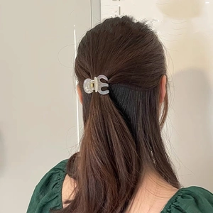 Close-up of a translucent marble-patterned claw clip styling brown hair in a half-updo