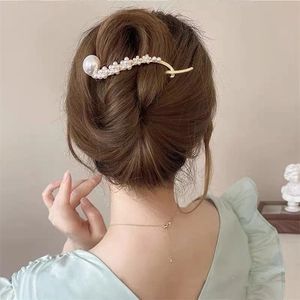 Elegante goudkleurige haarklem met parels getoond op een knotje van achteren gezien