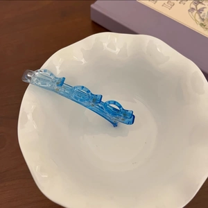 Gros plan d'une pince à cheveux bleue transparente à dents multiples dans un bol en céramique