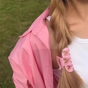 Pince à cheveux rose en acétate avec cœurs ajourés portée sur un chignon tressé