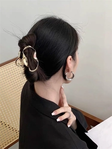 Detailed view of an irregular golden metal hair claw clip styled on a woman's low bun