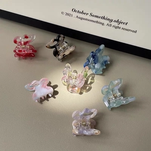 Detailed close-up of seven colorful mini butterfly hair clips with marble texture