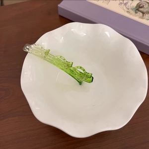 Détail de la pince à cheveux translucide vert émeraude avec design ajouré dans un bol