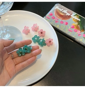 Dettaglio di mini mollette per capelli a fiore rosa e blu con perle e strass luccicanti