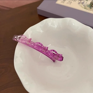 Détail macro d'une pince à cheveux violette translucide avec un design creux