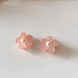 Dettaglio di fermagli per capelli a forma di fiore rosa con perla su sfondo neutro