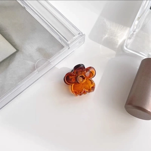 Top view of translucent amber flower hair claw clip on minimalist white background